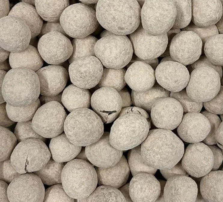 A close-up pile of classic round Bristows salted caramel bonbons lightly dusted in fine icing sugar and cocoa powder showing their light brown colour.