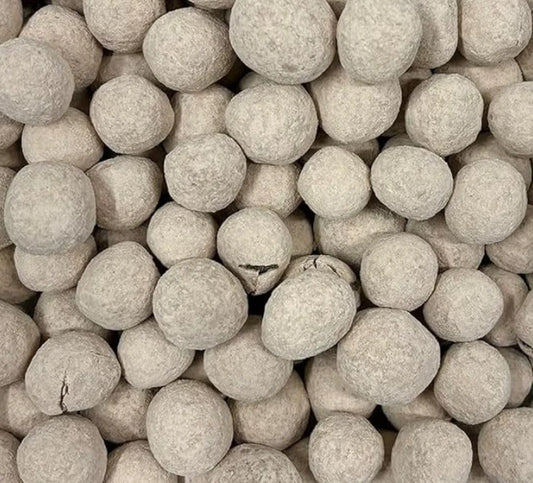 A close-up pile of classic round Bristows salted caramel bonbons lightly dusted in fine icing sugar and cocoa powder showing their light brown colour.